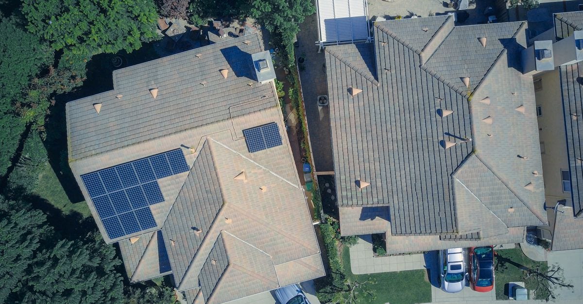 High pressure cleaning of a tiled roof revealing the original colour on a suburban home